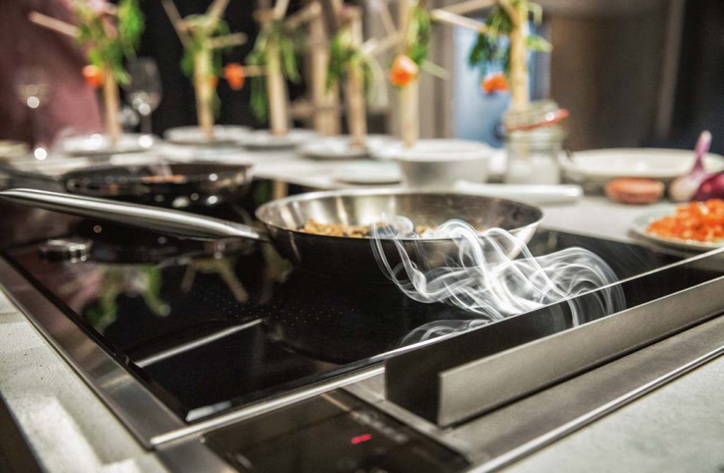 Eine dezente, aber sehr effektive Technik: Direkt neben dem Kochfeld eingefasst kann der smarte Abzug Dampf und Fett sofort aufnehmen. (Foto: epr/NEFF)
