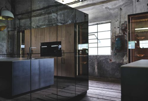 Schwarze Dekorglasfronten der Fero mit der Kücheninsel in „dark iron“ Foto: INTUO
