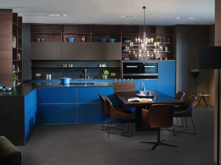 Die Kombination aus „pacific blue" und „tonka" besticht mit nobler Kühle. Der Materialmix aus Naturstein, matt satinierter Colorglas-Oberfläche und thermisch farbverändertem Holz in „arabica oak" wirkt dabei aber kein bisschen distanziert. Im Gegenteil: Er steht im Einklang mit sich selbst und schafft eine relaxte Atmosphäre. Foto: INTUO