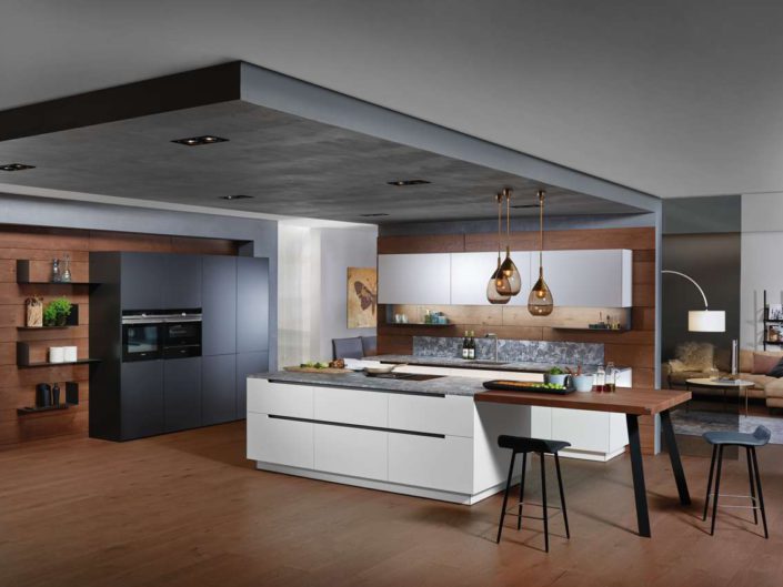 Die ewe50 wird als Kombination aus schlichtem weiß color, elegantem anthrazitgrau, einer Arbeitsplatte aus Marmor-Dekor und dunklem Parsolglas zum echten Blickfang. Der außergewöhnliche Stil durch seitlich abgeschrägte Stufenfronten setzt sich in den abgeschrägten, und auf Gehrung gesetzten, Frontwangen fort. Foto: ewe