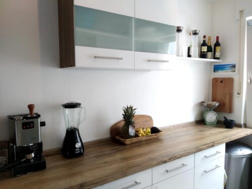 In romantisch-modernem Design treffen die Arbeitsplatten aus Zimt-Eiche auf moderne Hängeschränke in Weiß-Hochglanz und ergeben eine moderne Vintage-Küche. Foto: Küchen Journal