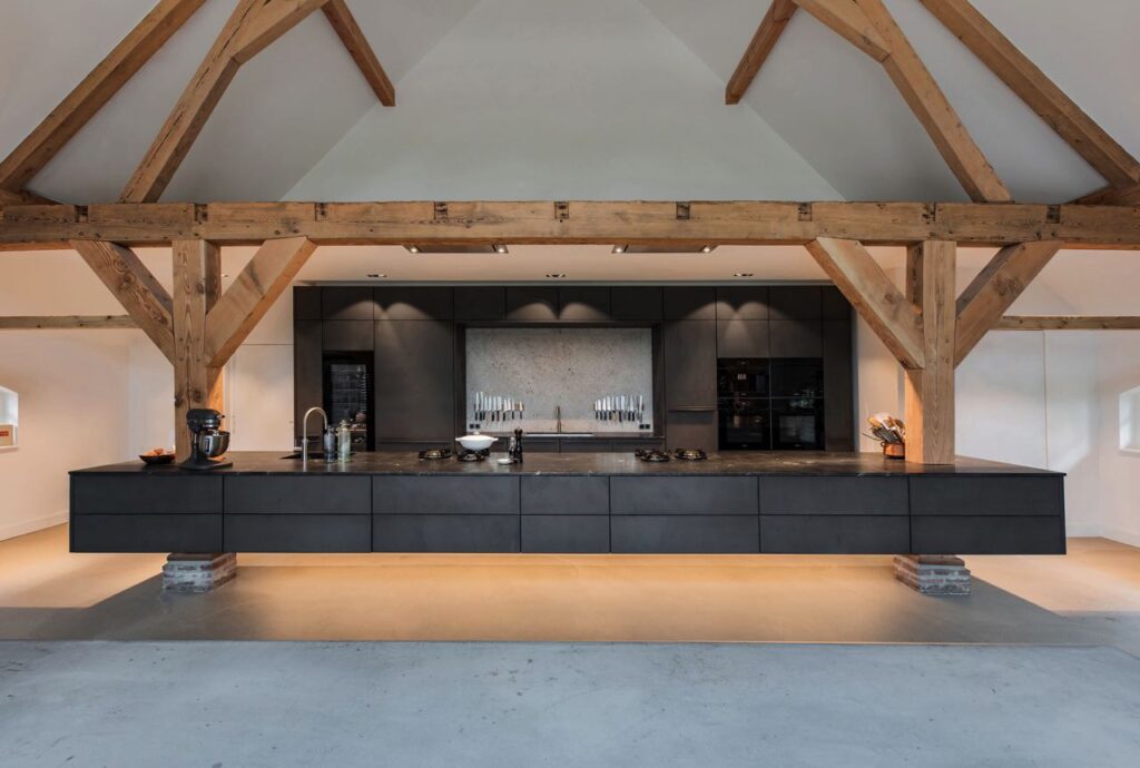 Warmes Holz und kühler Beton bilden die charakteristischen Materialien dieser modernen Küchenplanung, die mit einem schwebenden Raumeffekt spielt. Foto: GDandP Graphic Design and Photography