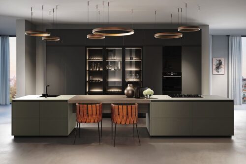 Entschleunigen mit Dusty Colours. Die raffiniert beleuchteten Glasschränke laden zum Erkunden ein und erzeugen eine sehr angenehme Atmosphäre in dieser Küche mit ihren extramatten Antifingerprint-Fronten. Foto: AMK   