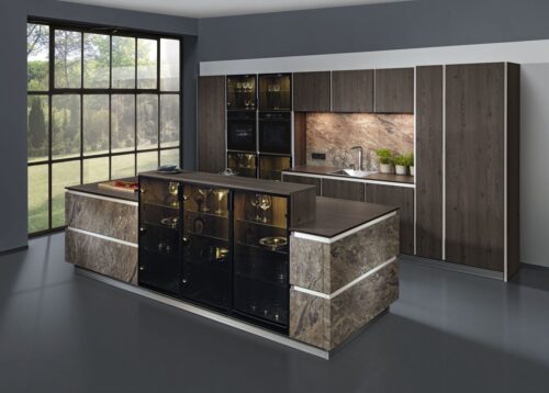 Eine pfiffige Lösung: Im Vordergrund eine Kücheninsel mit höher stehenden Glasschränken, die gleichzeitig als Theke und Sichtschutz dienen – im Hintergrund eine Kombination von Vitrinen und Einbaugeräten. Foto: AMK