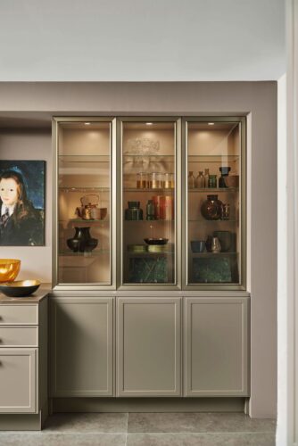 Repräsentative Lifestyle-Wohnküche in einem modern-klassischen Mix mit Vitrinentüren in bronzefarben getöntem Glas und perfekt darauf abgestimmten Rahmen, was den edlen Gesamteindruck dieser Planung verstärkt. Foto: AMK