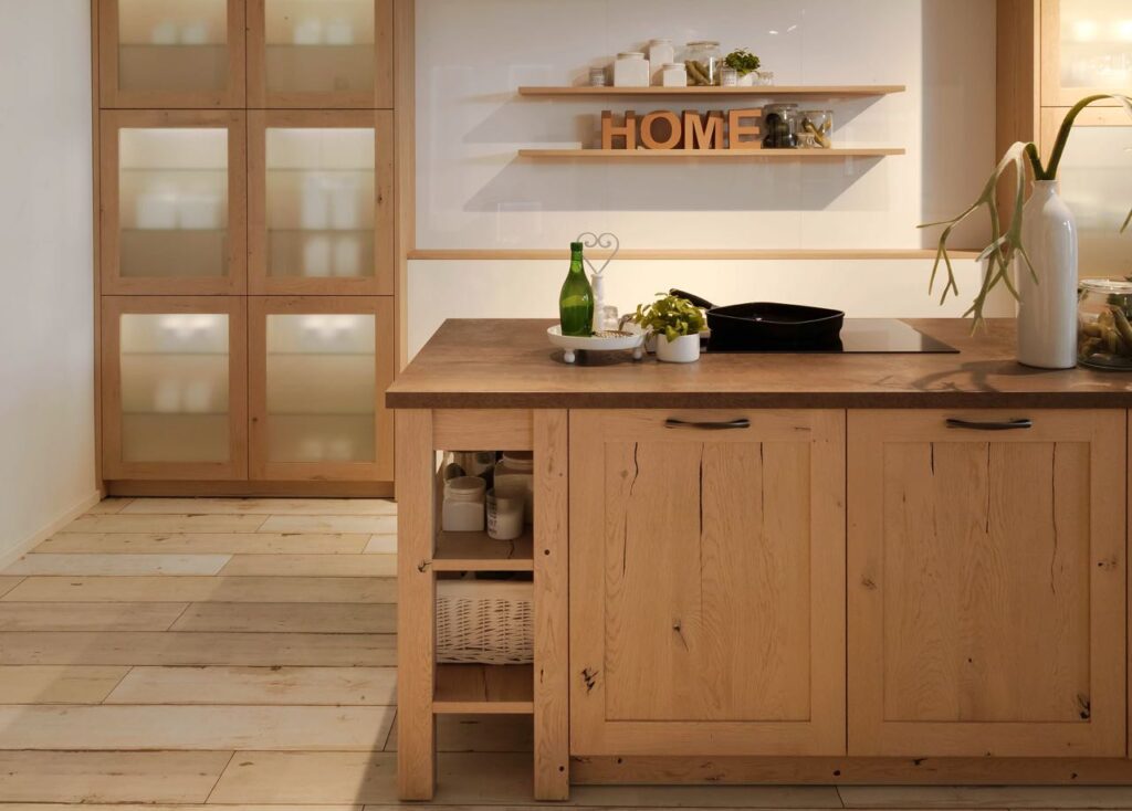 Im Scandinavian Style: Wohnliche Küche in Echtholz mit hohen, grifflosen Vitrinenschränken. Hinter den Rahmentüren mit Glasfüllung (Milchglas) lassen sich die Porzellan- und Glaswaren eher erahnen. Foto: AMK