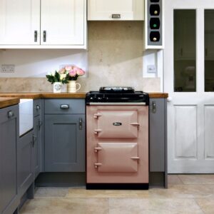Der Rangecooker in der Farbe „Blush“ von AGA setzt ein Farbstatement in der sonst eher schlichten Landhausküche. Foto: AGA