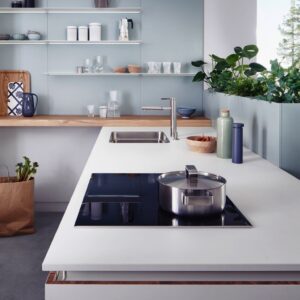 Landhaus meets Skandi-Style: Die schlichte Küche wirkt durch die Holzplatte und die Metallregale richtig wohnlich. Auch die Grünpflanzen prägen den Stil. Küche von Leicht. Foto: Leicht