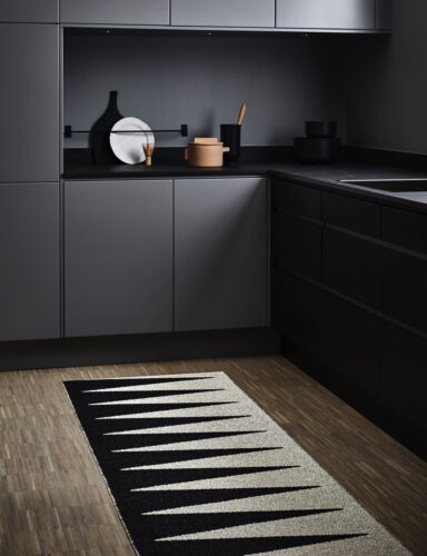 Detail in Weiß zur vorwiegend schwarzen Küche: Der Teppich „Vivi“ von Pappelina, ca. 140 Euro. Foto: Pappelina