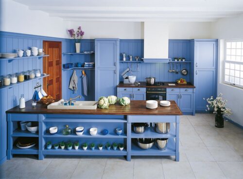 Der Kombipartner Holz macht sich gut in der Küche „Maryville“. Er ist allerdings nur Nebensache in dieser himmelblauen Küche im Landhaus-Look. Besonders sind Kleinigkeiten, wie zum Beispiel die Regale. Foto: Schmidt Küchen