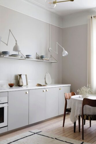 Schlicht und schön, alles sieht wie aus einem Guss aus. Die fehlenden Oberschränke ersetzt das Design-Regal und lässt die Küche besonders leicht wirken. „Ingaro Kitchen“ von Helsingo in der Farbe „Feather Grey“.