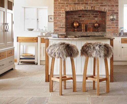 Sieht schön aus und wärmt noch: Legen Sie hübsche Felle oder Fellkissen auf die Stühle. Alternativ wärmen auch Samt- oder Strickkissen.
Die Hocker fallen mit ihren tollen Fellkissen gleich ins Auge. „Gwyn Baa Sheepskin Bar Stool“ von Lime Lace.