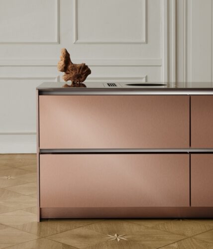 Durch das matte Roségold wirkt die Küche „S2“ von SieMatic regelrecht verspielt und passt schön zur Jugendstilarchitektur des Raumes. Auch die Arbeitsplatte aus kaltgewalztem Edelstahl hat die gebürstete Optik.