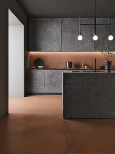 Dunkle Beton-Fronten wirken industriell. Verstärkt wird das noch durch die Fliesen „Foil“ aus Feinsteinzeug in Cortenstahl-Optik von Ceramiche Refin. 