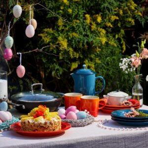 Hier ist ja richtig was los und es wurde nicht an Farbe gespart! Reichlich Geschirr, Eier und Blüten tummeln sich da. Auch der Kuchen mit Blüten sorgt für Stimmung. Und wenn dann noch die Sonne scheint, fühlen sich Familie und Freunde gleichermaßen wohl. Alles von Le Creuset.