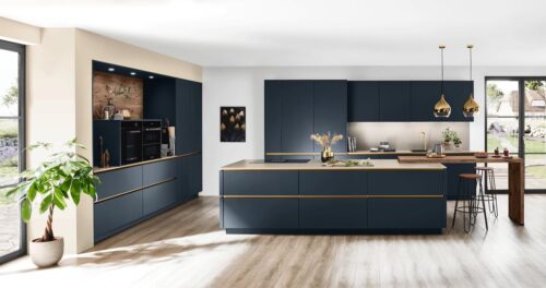 Edel wirkt die Küche „Easytouch“ von Nobilia. Das liegt am dunklen Blau, aber insbesondere an der Kombination mit Gold. Es findet sich in den Griffkanten und wird durch Accessoires und die Lampen ergänzt. 