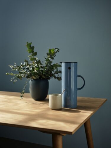 Die Thermoskanne von Stelton im Farbton „Dusty Blue” harmoniert perfekt zur gleichfarbigen Wand. Das Ambiente ist skandinavisch wohnlich.