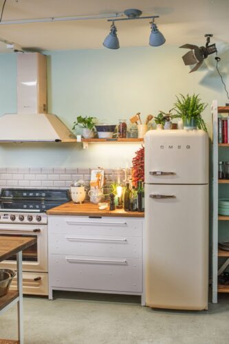 Smeg Küchengeräte in dezenten Naturtönen und die weißen Stahlmöbel Authentic Kitchen: ein starkes Duo für den Industrial Style. Foto: Smeg