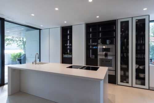 Hinter praktischen auch mit Dekton® verkleideten Taschentüren verbirgt sich der beleuchtete Stauraum für Geschirr, Backofen, Mikrowelle & Co. So sieht die Küche immer aufgeräumt und ordentlich aus. Foto: Schmid Baugruppe Holding GmbH, 2021