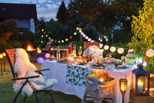 So ein liebevoll gedeckter Tisch verströmt Ferienatmosphäre. Das liegt auch am dekorativen Geschirr, am Kissen mit Muscheldruck, den Cocktails und Lichterketten. Alles von Baur Home.