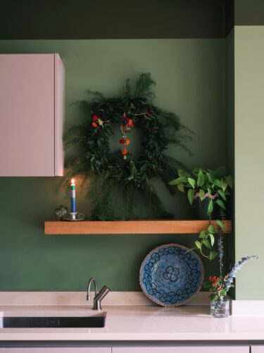 Die Ecke über dem Board bietet sich perfekt an für den Kranz. Er ist ein echter Hingucker mit seiner sehr modernen Form und den niedlichen Bommeln. Wandfarbe von Farrow & Ball.