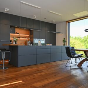 Der Materialmix der puristischen Küche wirkt sehr harmonisch. Das Holz bringt Wärme in den Raum. Foto: Thorsten Franzisi / LEICHT 