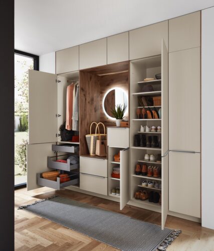 Hochwertiger Stauraum für Schuhe, Jacken und Taschen, den erzielt man mit den Küchenelementen aus der Serie „Riva“ von Nobilia. Besonders schön ist die aufgelockerte Optik mit Holzverkleidung und beleuchtetem Spiegel.
