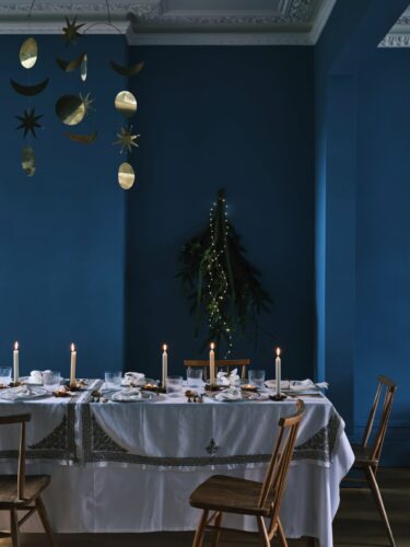Ein bisschen wie aus Großmutters Geschirrschrank wirken Gläser, Teller, Besteck und Geschirr. Unterstützt wird der nostalgische Charme außerdem von niedlichen Kerzenständern und den alten Möbeln. Harmoniert gut dazu: die blaue Wandfarbe von Farrow & Ball.