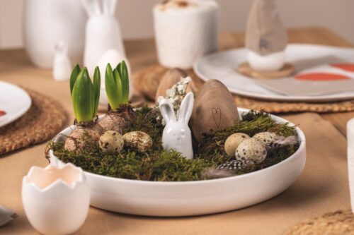 Da lugt das Häschen aus Moos, Eiern, Federn und Zwiebelpflanzen hervor. Alles liegt zusammen in der Hasenschale „Ostern“ aus Porzellan von Räder, ca. 35 Euro.