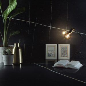 Eine kleine Tischleuchte kann punktuell für Helligkeit sorgen. Das ist zum Beispiel hilfreich, wenn das Rezept nachgelesen werden soll, die Beleuchtung ansonsten aber eher gering ist. Die hübsche Wand und Arbeitsfläche heißt „Silestone Eternal Noir“ von Cosentino.