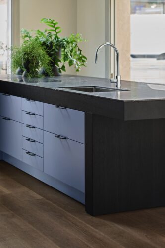 Die architektonische Formensprache fällt hier gleich ins Auge. Das Violett-Blau erhält durch Schwarz eine gewisse Schwere und Eleganz. Kleine Besonderheit: Die Eichenplatte in Schwarzmatt hat eine schmale, nur 12 Millimeter dicke Auflage in Quarzit Negresco. Serie „Mondial“ von SieMatic.