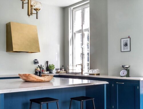 Die Dunstabzugshaube UNIKA von trepol in gebürstetem Messing macht sich gut mit der Armatur und anderen Accessoires aus demselben Metall. In Kombination mit der blauen Küche entsteht eine harmonische und elegante Atmosphäre.
