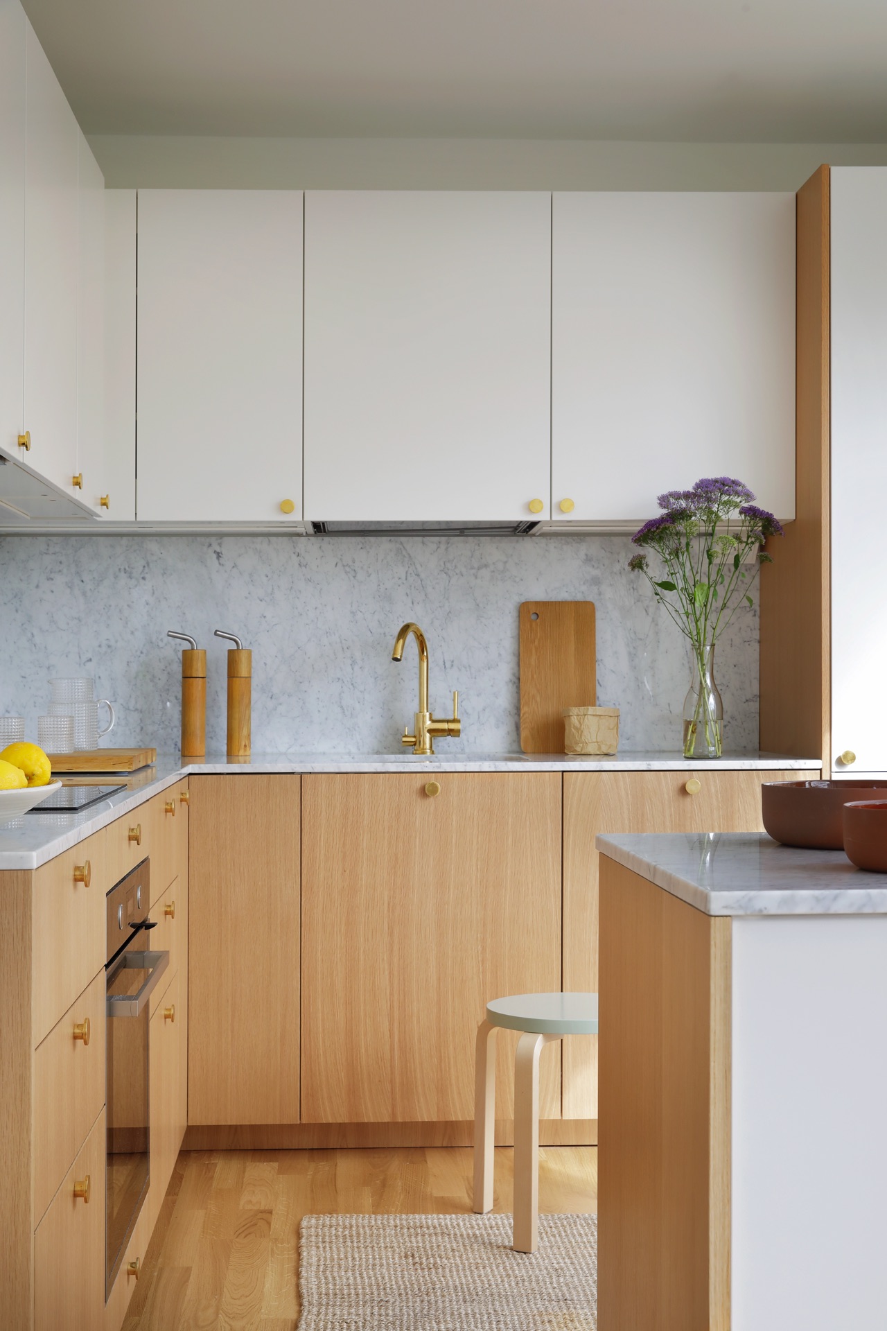 Spiegelt geschmackvoll Skandi-Stil wieder: die Küche „Ingarö“ von Helsingö. Dazu trägt die Kombi aus Weiß und hellem Holz bei und die goldfarbenen Akzente, abgerundet durch eine Prise Marmor.