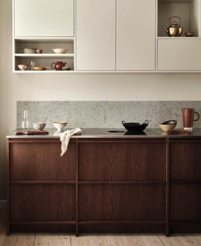 Die Edelstahlarbeitsfläche, die Rückwand aus Marmor und die weißen Oberschränke lockern die Strenge der dunklen Küche auf, die mit ihren gleichmäßigen Profilen begeistert, von Nordiska Kök.