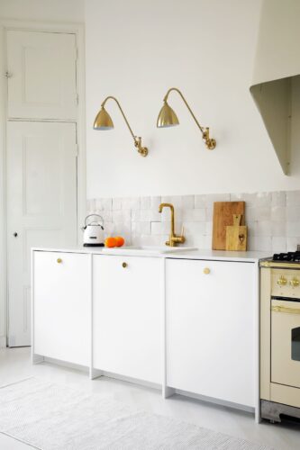 Selbst der Boden und die Wand sind hier Weiß gehalten. Ein Blickfang ist auch der alte Schrank mit Kassetten. Wunderbar wertig sieht die Küche mit Gold als Partner aus. Aus der Linie „Ingarö“ von A.S.Helsingö.
