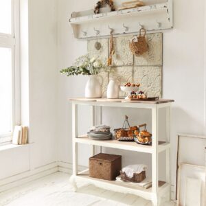 Landhaus, aber bitte gemütlich! Das erreicht man mit Details. Die Anrichte dient als Ablage und Fläche für Deko-Elemente, wie eine Vase. Die Haken schaffen zusätzlichen Stauraum, das Shabby-Regal sorgt für eine persönliche Note. Alles von Loberon.