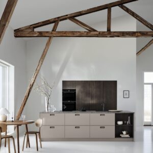 Eingefasst von Marmor, unterstützt von dunklem Holz – so präsentiert sich die Küche „Avolia“ in Beige von Kvik. Das wirkt ausdrucksstark.