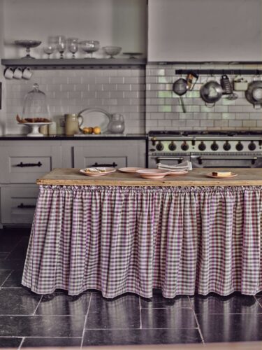 Etwas ländlicher als Blumenmuster sind Karos. Auch sie können für einen romantischen Look stehen. Eine hübsche Idee ist es, die Kücheninsel mit einem Vorhang zu umranden. Dahinter kann einiges verschwinden und es sieht ordentlich aus. Von Tori Murphy.