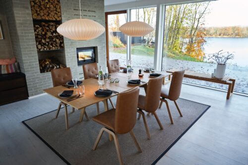 Integriert in ein großzügiges Ensemble ist der kleine, kompakte Kamin. Die Extra-Fächer für das Brennholz sind hilfreich und sorgen auch optisch für Wärme. Die Esszimmer-Möbel sind von Stressless.