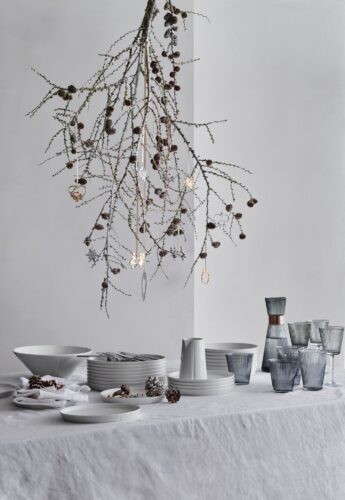 Eine interessante Dekoration: So niedlich wirken die silber- und goldfarbenen Ornamente, die am Lärchenzweig hängen. Das Geschirr ist geschmackvoll für einen Weihnachtstisch in hellen Tönen. Alles von Rosendahl.