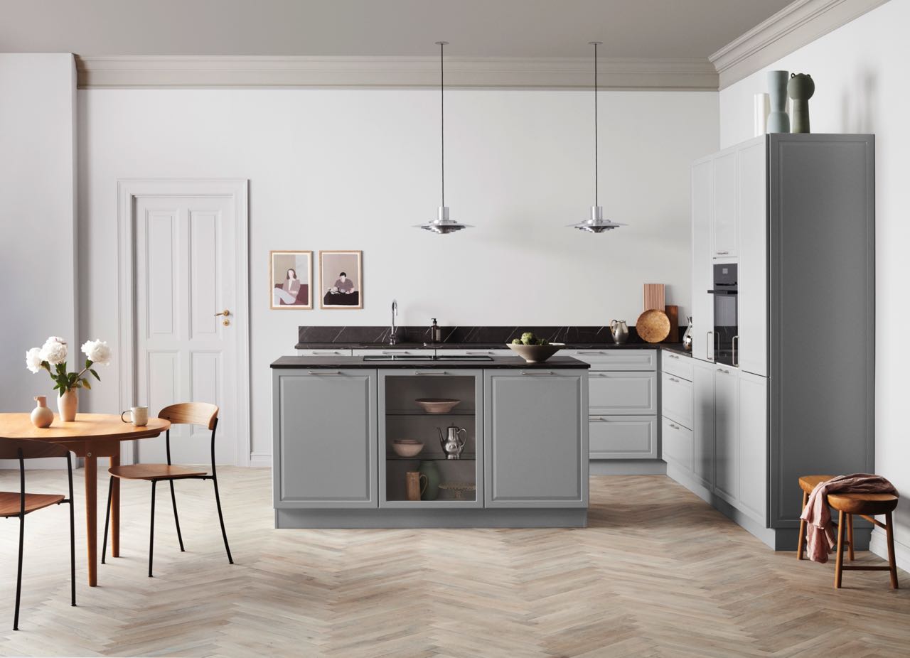 Die Küche lebt von hohen Schränken und der Einfachheit der Aufteilung. Der restliche Raum bildet einen tollen Kontrast mit dem warmen Holz, während die Möbel selbst in kühlem Grau modern aussehen. Die nachhaltige Küche ist von Kvik.