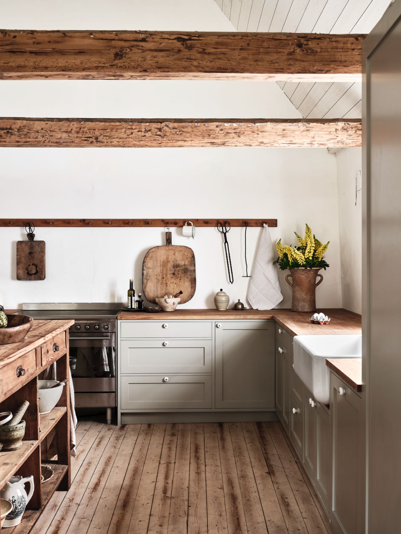Trotz der Landhausbalken und einiger Hinweise auf den Stil ist die Küche von Nordiska Kök doch eher dem Shaker-Look zuzuordnen. Das liegt an der Schlichtheit der Möbel, den Formen und der Farbe.