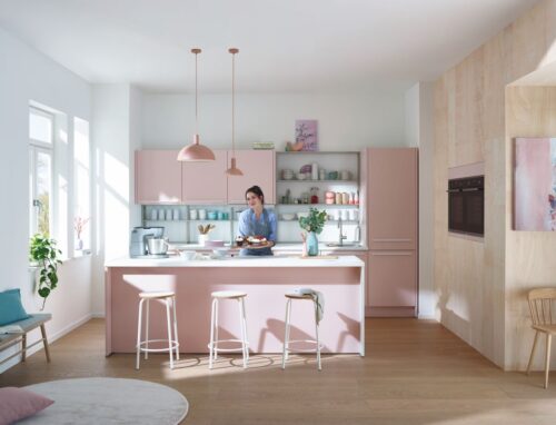 Richtig jung ist die Ausstrahlung der Küche von Küche & Co. Verstärkt wird das durch das helle Holz an der Wand und die modernen Accessoires wie Teppich, Geschirr, Lampen oder Hocker. 