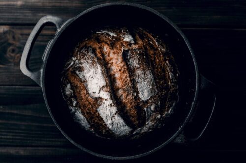 In dem schwarzen Gusseisenbräter ruht ein prächtig aufgegangenes Bauernbrot, dessen knusprige Kruste von der gleichmäßigen Wärmeverteilung und der hervorragenden Wärmespeicherung des Bräters zeugen. Foto: Artur Rutkowski auf Unsplash