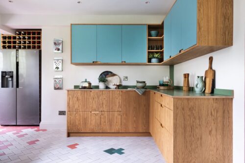 Hier wurde Mut zur Farbe bewiesen und dennoch ist nichts zu überladen. Ein gelungenes Ensemble bilden die Holz- mit den türkisfarbenen Fronten und der grünen Arbeitsfläche. Attraktiv sind die Koralle farbenen und blauen Details auf dem Boden. Küche von Wood Works.