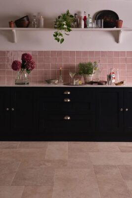 Sogar romantisch kann eine schwarze Küche aussehen, das zeigt die Landhausküche, die mit rosa Fliesen an der Wand und Fliesen in Beige auf dem Boden zusammenspielt. Unterstützen kann man den Look mit verspielten Blumen oder Bildern. Fliesen „Wild Rose Square“ von Marlborough Tiles.
