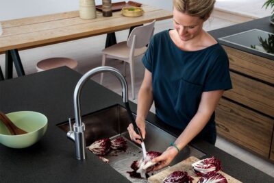 Eine hohe Funktionalität unterstützt die ganze Familie. Eine Idee ist eine schlaue Armatur. Zum Beispiel mit ausziehbarem Schlauch, um Gemüse und Obst besser abspülen zu können oder Töpfe zu füllen. Außerdem kommt heißes Wasser für Tee gleich aus dem Wasserhahn. Damit sich keiner verbrennt, hat die Armatur eine Kindersicherung, von Quooker.