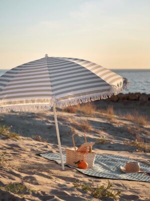 Ein Sonnenschirm ist ein Top-Schutz an heißen Tagen. Nur zu windig darf es nicht werden, damit er im Sand-Boden verankert bleibt. Er kann auch mit Schnüren und Heringen zusätzlich befestigt werden. Von Søstrene Grene.
