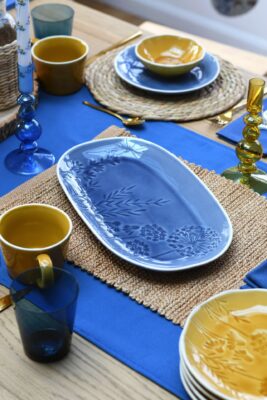 Lebendig wirkt die Kombination aus meeresblauem und sonnengelbem Geschirr und Accessoires. Besonders niedlich sind die Abdrücke von Gräsern und Blüten auf dem Geschirr. Alles von Gisela Graham.