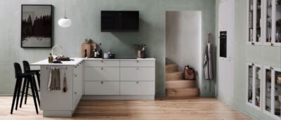 Eine Küche in L-Form muss nicht unbedingt an der Wand stehen, das beweist diese Aufteilung aus Zeile und dazugehöriger Sitzmöglichkeit. Durch die Zimmerstruktur mit der Treppe bietet sich diese Idee perfekt an und wird durch die Einbauschränke in der Wand ergänzt. So ist auch genügend Stauraum vorhanden. Küche von Veda.